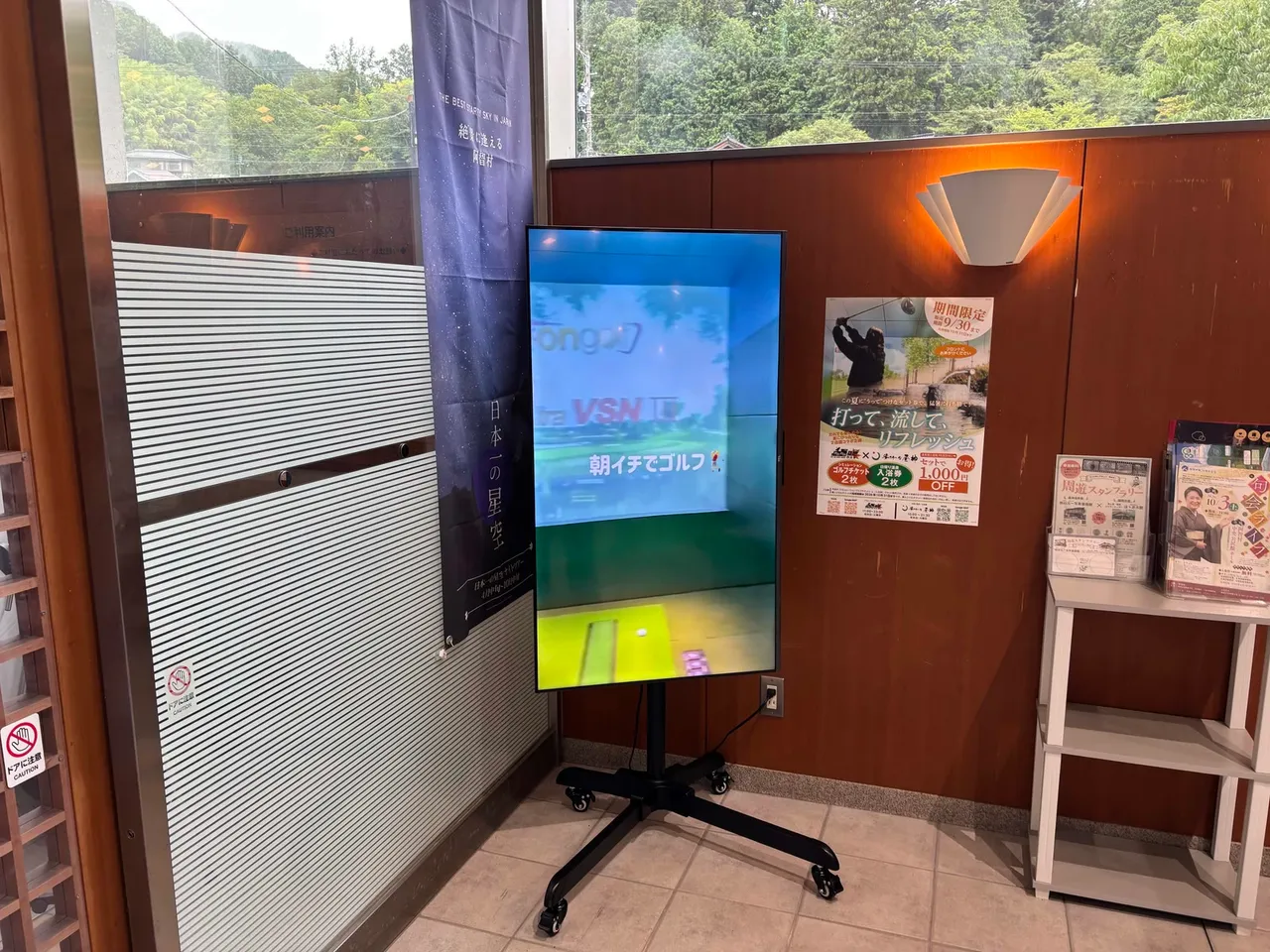 温泉施設の館内に置いた縦向きのディスプレイ。ゴルフの案内動画が流れている