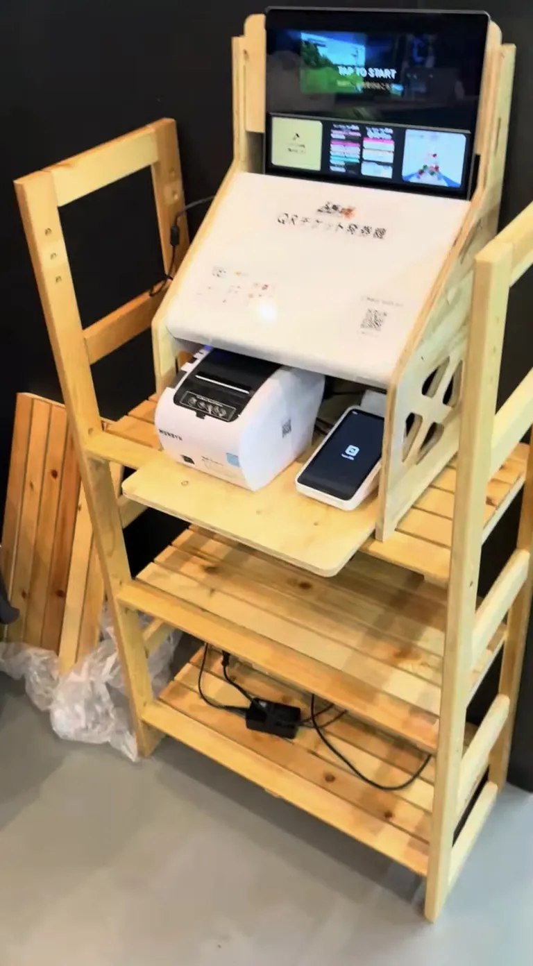 ACHI BASE に置いた店外の発券端末。上からタッチ画面、QRチケットの発券口、感熱式プリンター、決済端末が縦に並んでいる